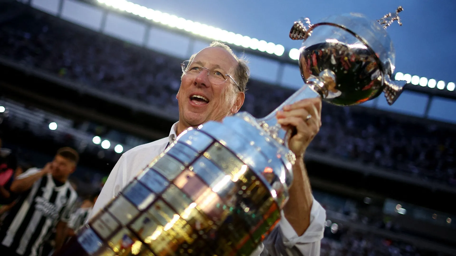 John Textor tại một sự kiện liên quan đến mua bán câu lạc bộ, mô tả nhà đầu tư người Mỹ với sân khấu bóng đá